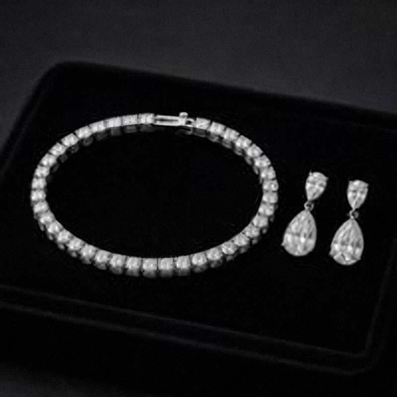 Diamond tennis bracelet and pear-shaped earrings on black velvet